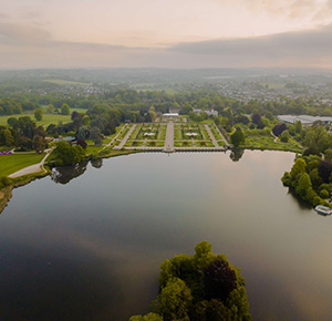 Image shows an aerial shot of the lake and gardens at The Trentham Estate, with the city of Stoke-on-Trent in the background
